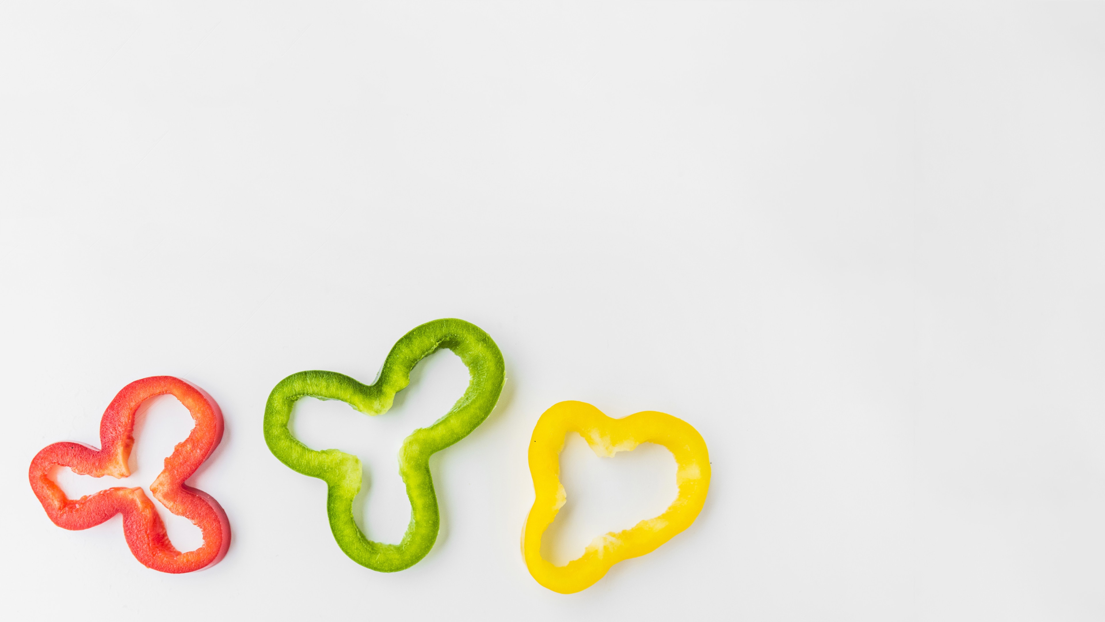 Sliced red green and yellow bell peppers on white background