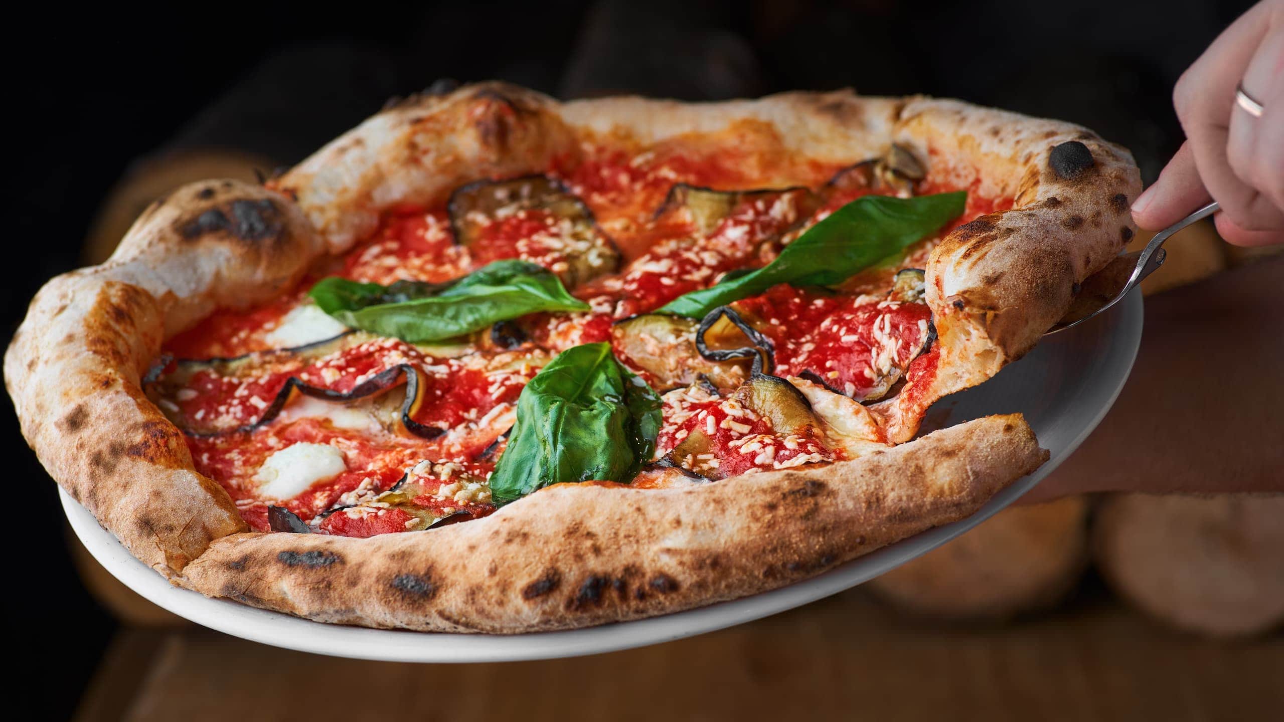 Traditional Italian Vito Iacopelli pizza dough with eggplants, mozzarella, basil, and tomato sauce