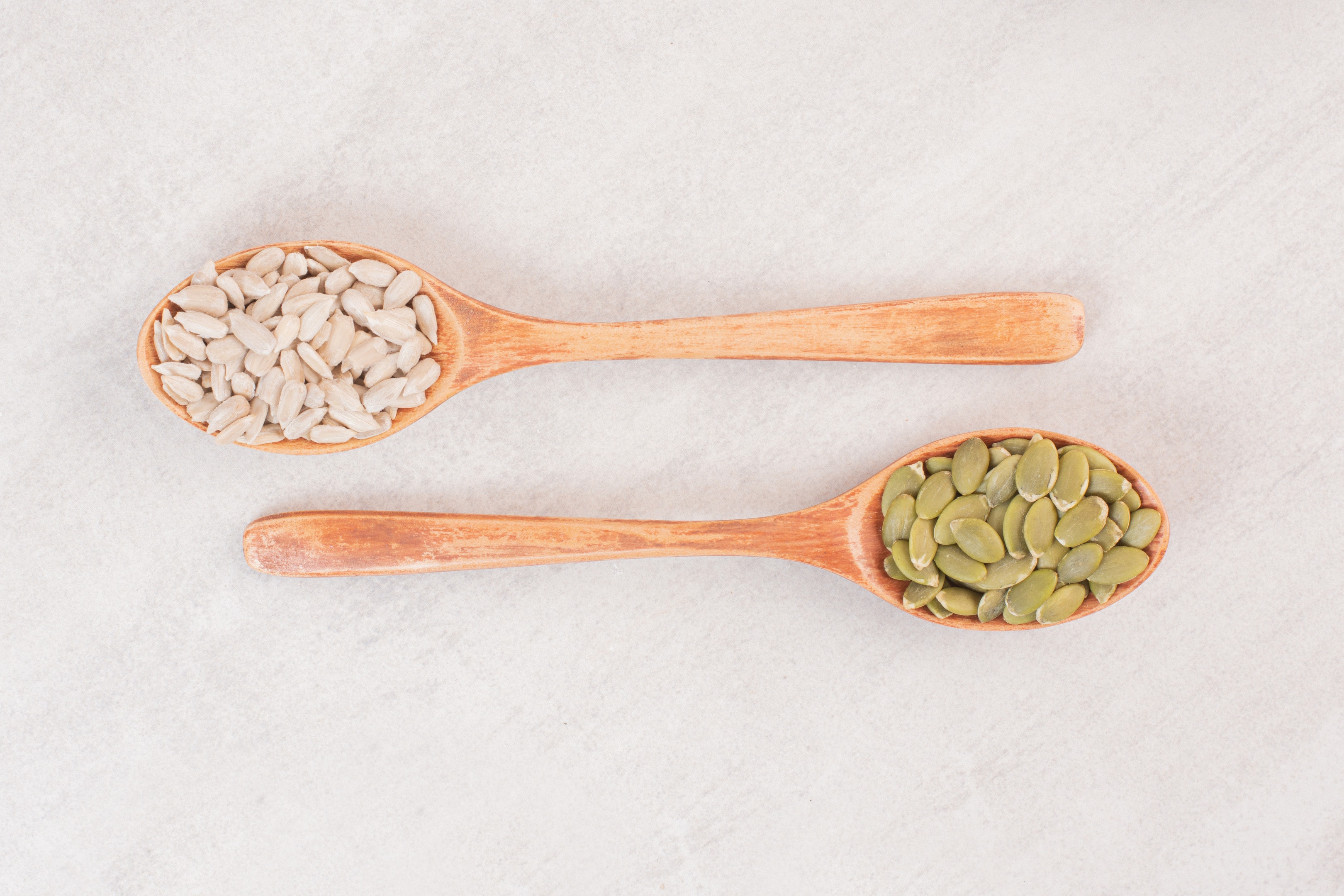 Sunflower and pumpkin seeds in wooden spoons