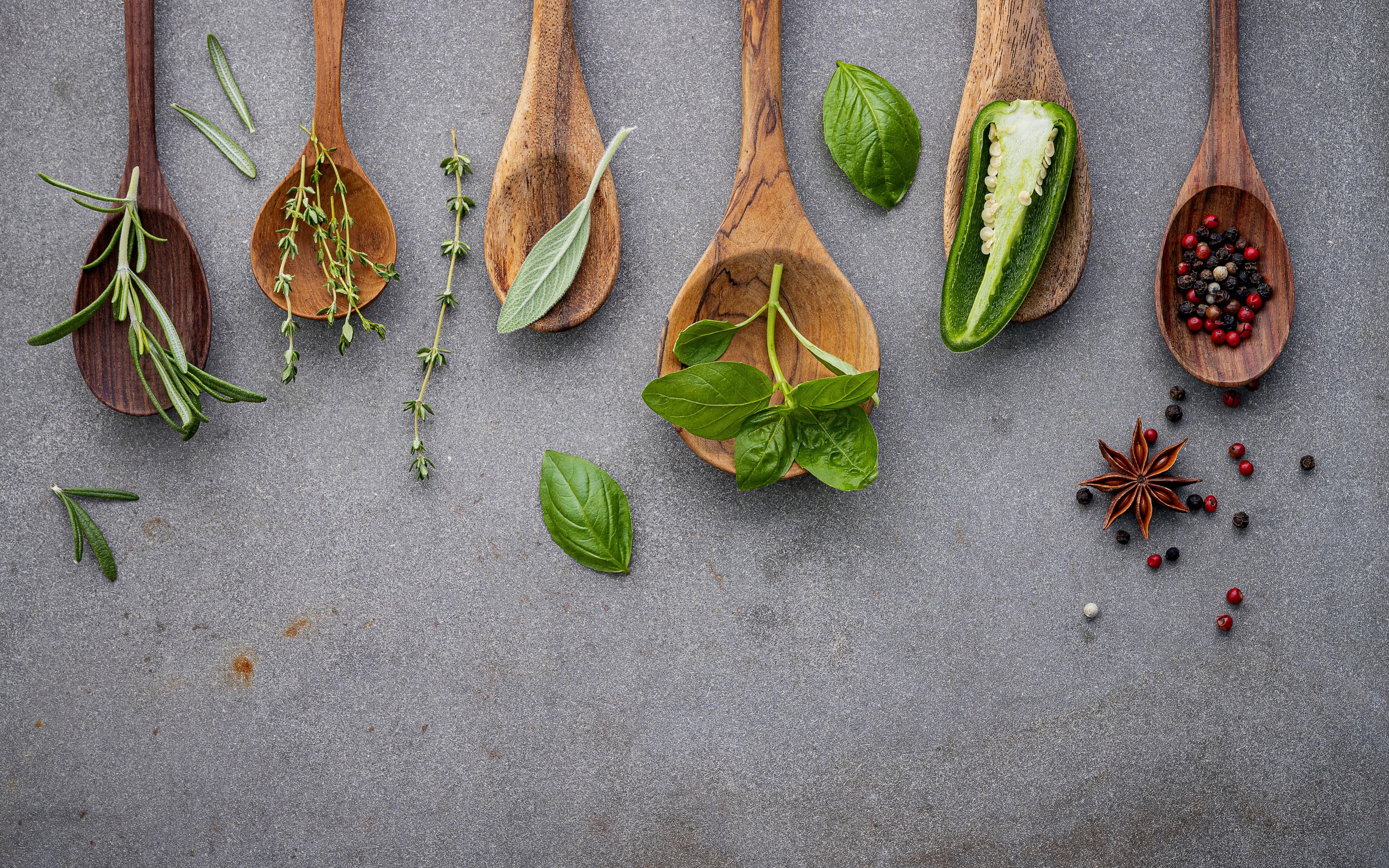 Various spices and herbs on wooden spoons