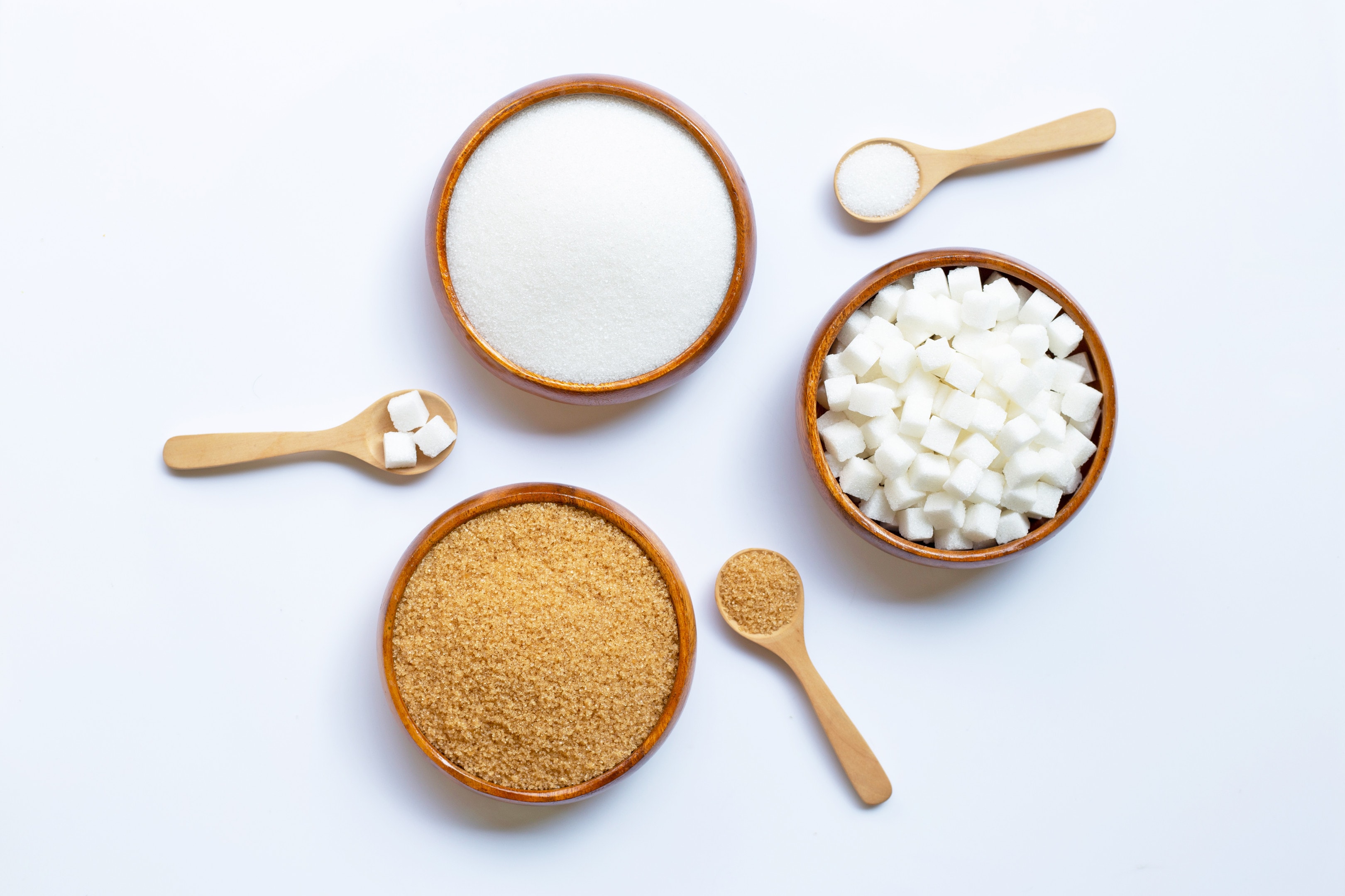 Various types sugar in wooden bowls on white background