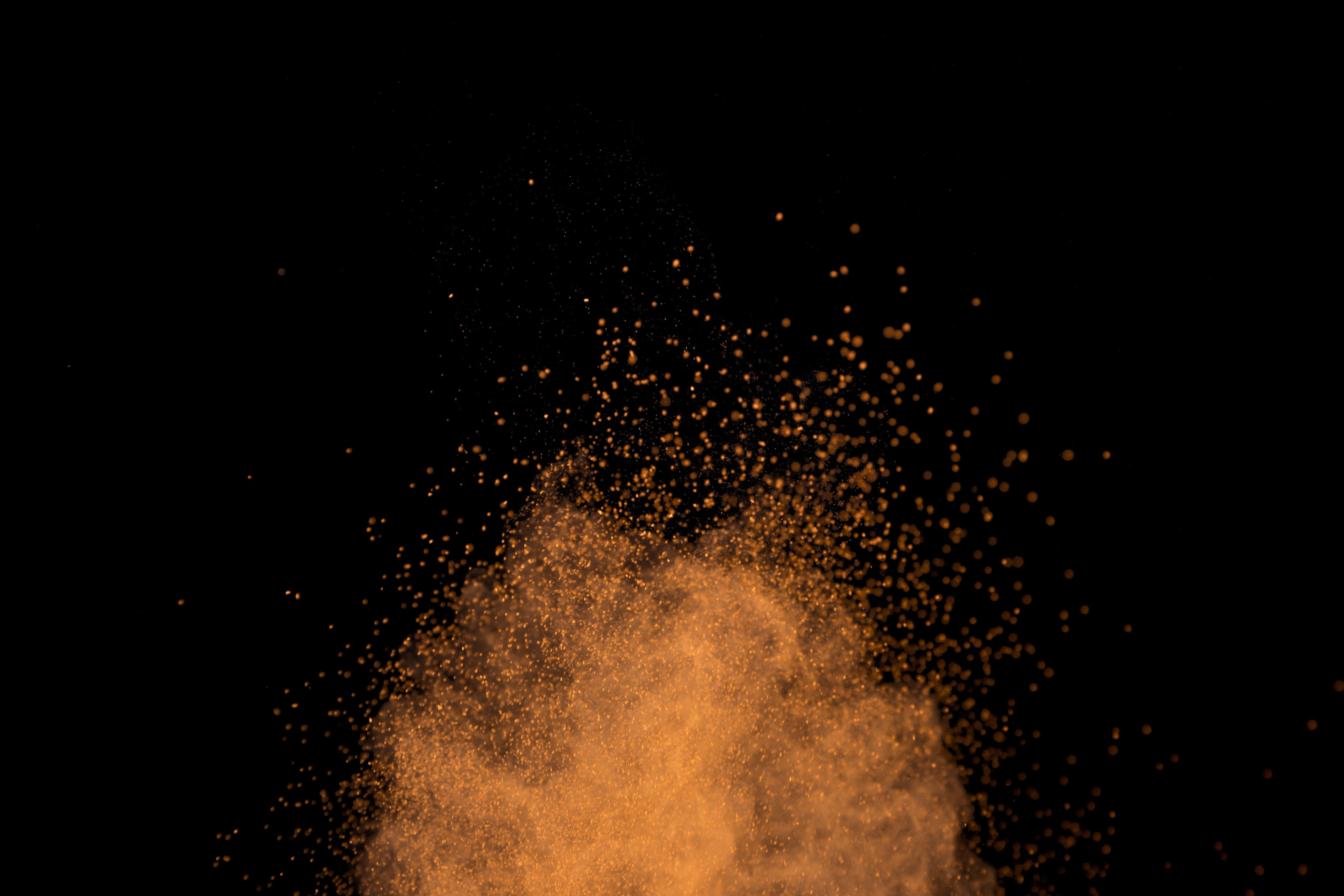 Vibrant cloud of mango powder on black background