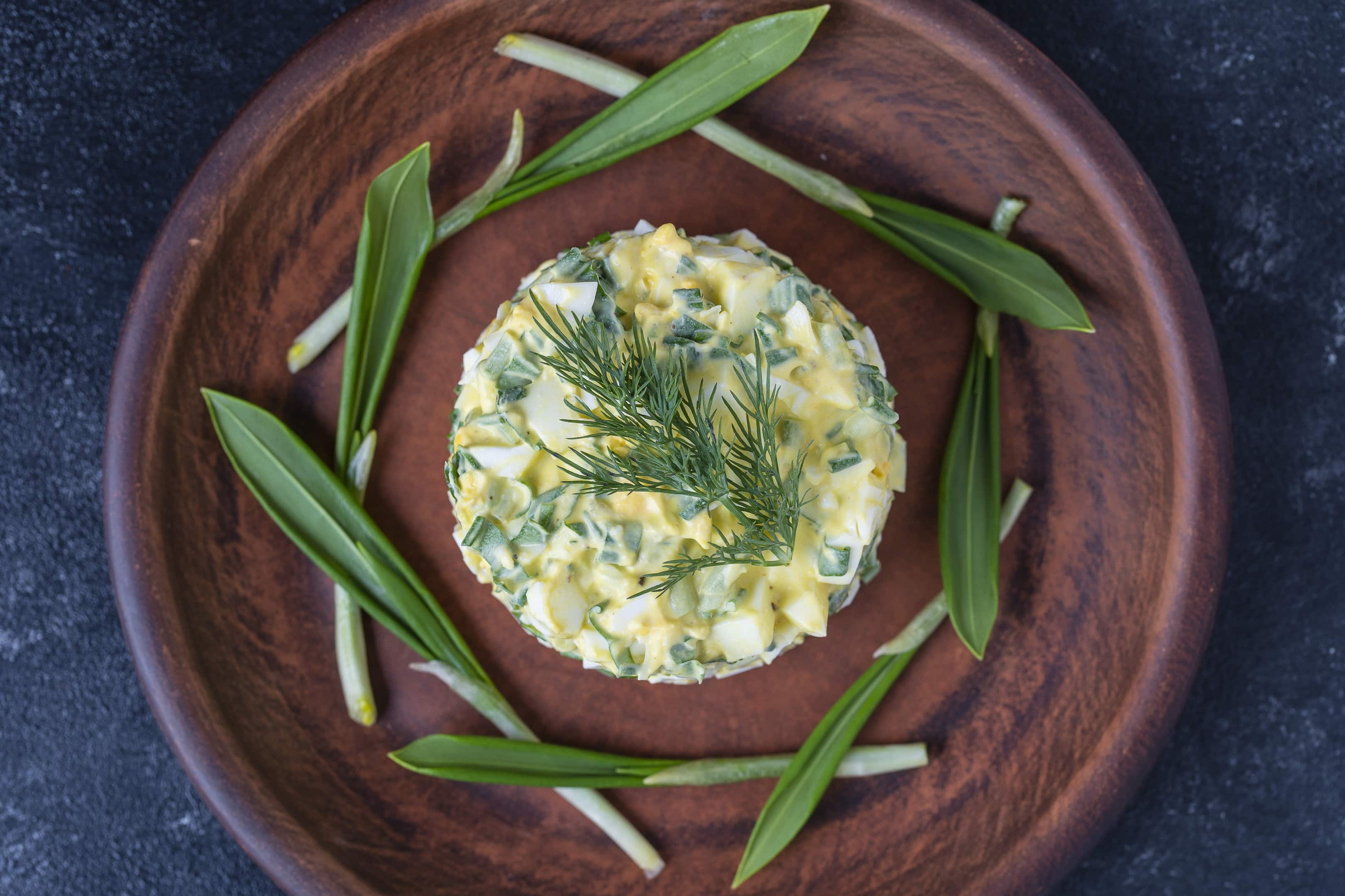 Wild garlic salad with green wild leeks, boiled eggs and sour cream