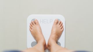 Person standing on white scales with the word help
