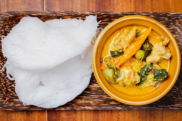 Balinese-style coconut curry in a bowl with rice noodles