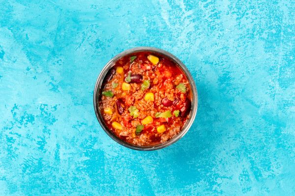 Bowl of chili con carne on a blue background
