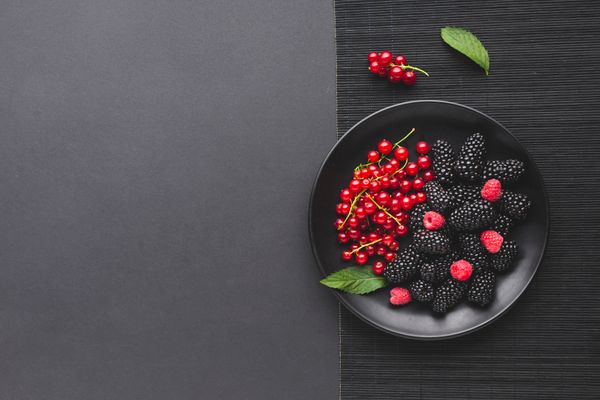 Flat lay plate of fresh berries on wooden table