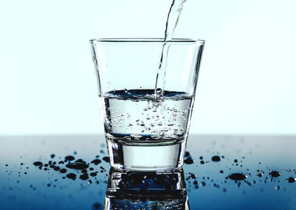 Glass of water with pouring water
