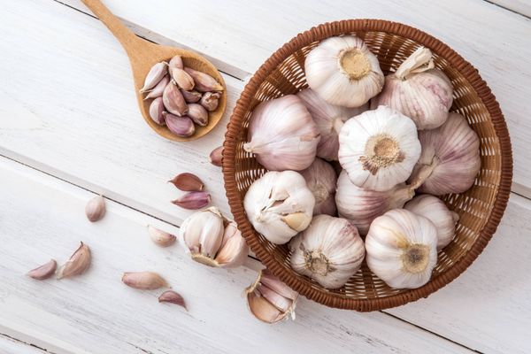 Group of garlic in wooden plate on white wooden table