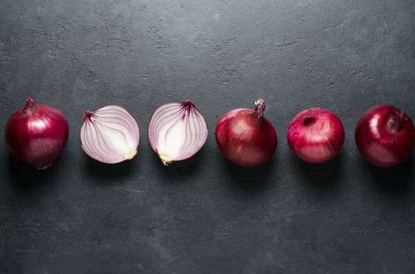 Red onion whole and sliced on black background