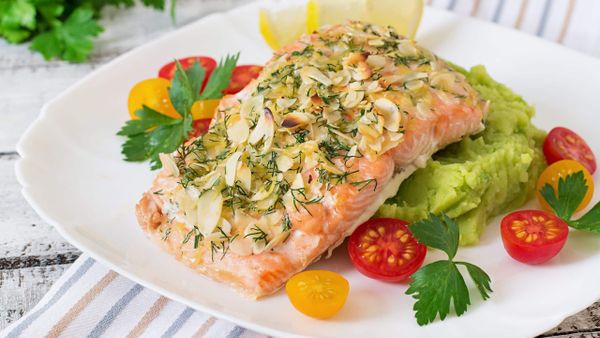 Stuffed salmon with crabmeat and shrimp garnished with cheese, almond crust, and veggies