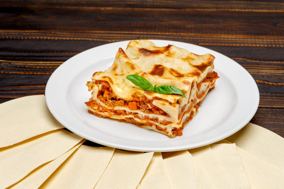 Slice of lasagna on a wooden surface