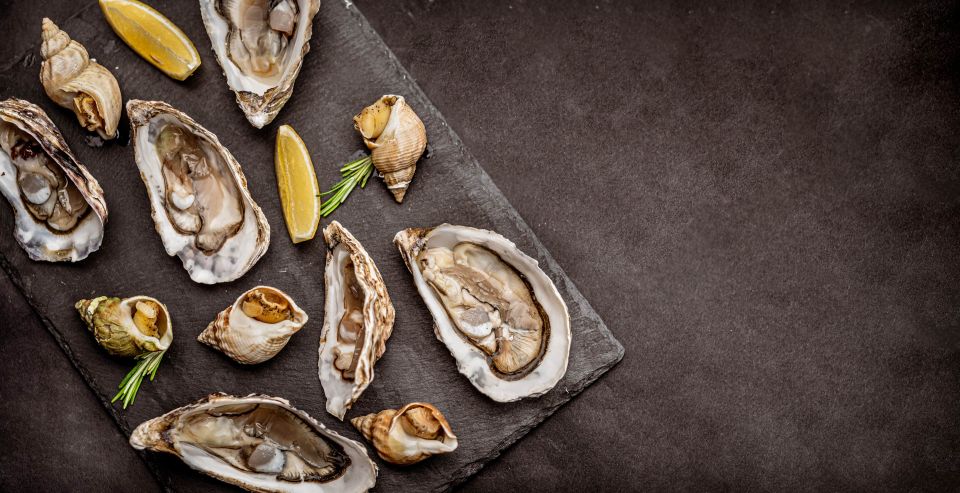 Raw oysters with cooked snails on black platter