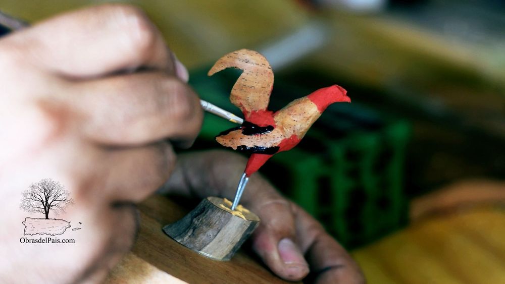 Carlos pinta una pequeña talla de gallo en madera