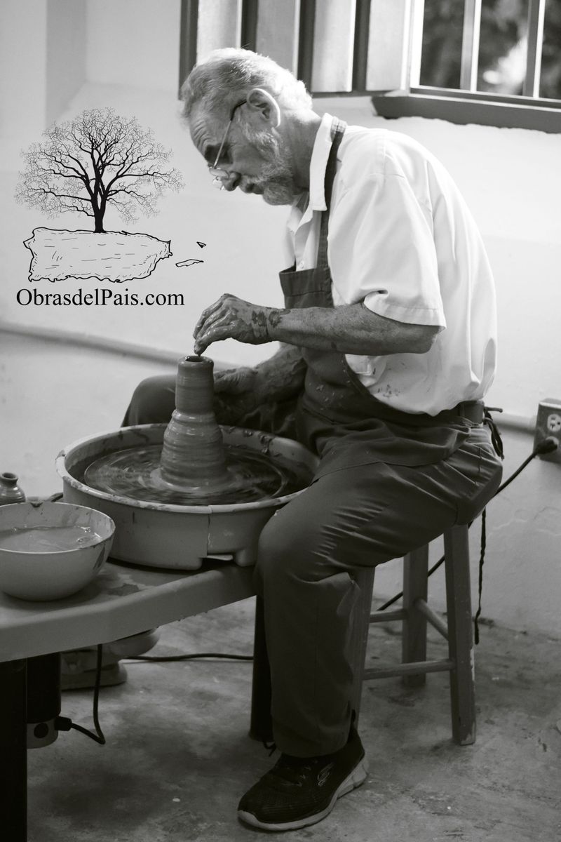 Nicholas Damiani sentado frente al torno trabajando una pieza de barro en su taller
