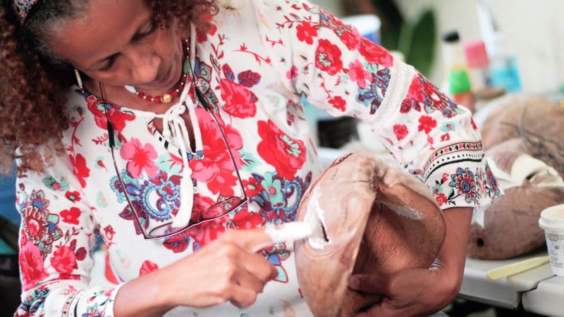 Wilda Cruz trabajando la terminación interior de una máscara de vejigante en coco