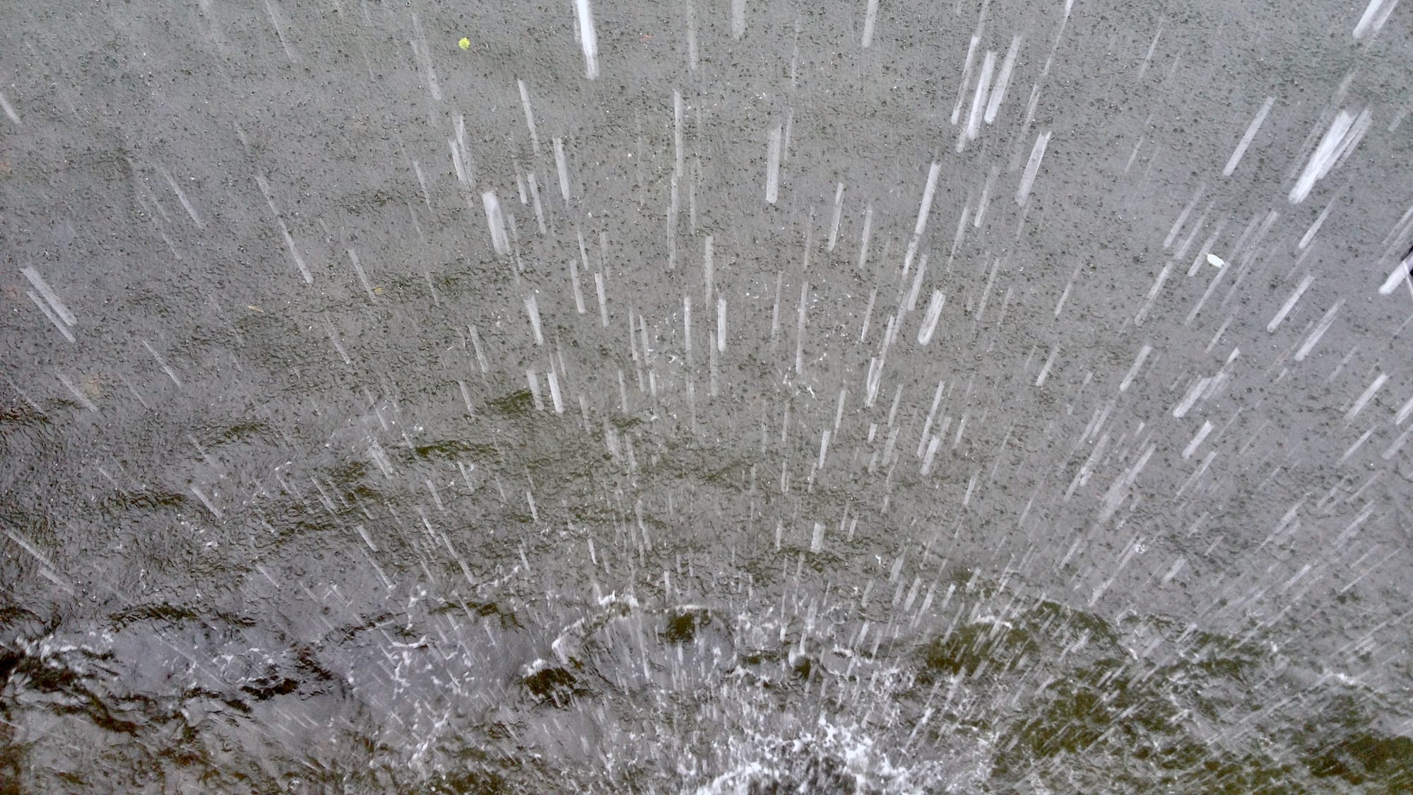 Rain falling into a pretty gloomy looking body of water.