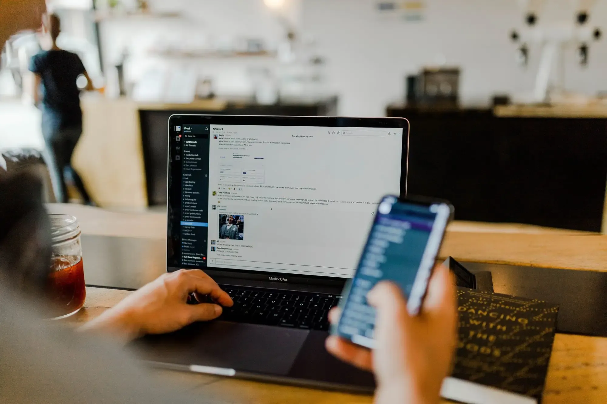 A person using Slack on his laptop and smartphone