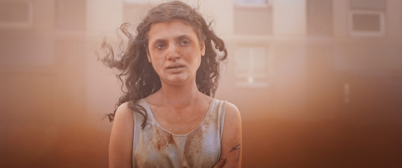 Melissa Boros stands in red mist in the film Alpha
