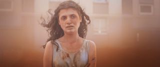 Melissa Boros stands in red mist in the film Alpha