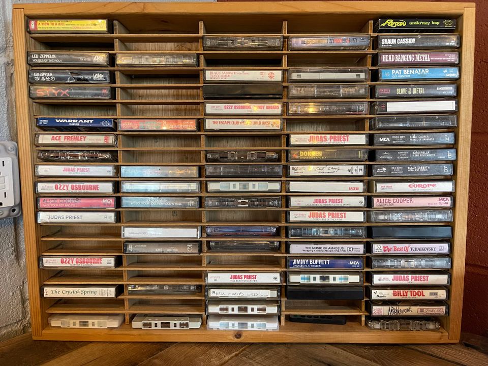 A wooden rack of cassette tapes—titles include selections by Ozzy Osbourne, Judas Priest, Warrant, Europe, and The Escape Club. Also some Mozart and Tchaikovsky for good measure.