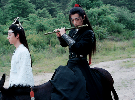 Animated gif from The Untamed featuring Wei Wuxian riding a donkey and playing a flute while Lan Wangji walks beside him.