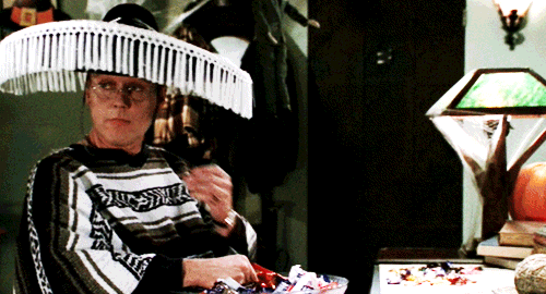  An animated gif of Giles wearing a sombrero and snacking on Halloween candy. 