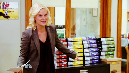  An image of Amy Poehler as Leslie Knope in Parks and Rec, gesturing towards many color-coded binders. 