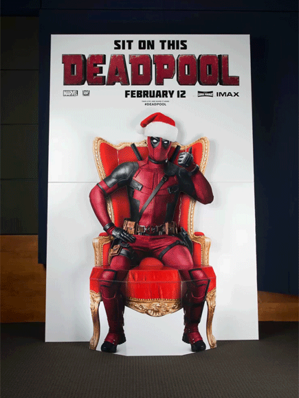  An animated gif in which Ryan Reynolds mugs against a  Deadpool  standee featuring an incorporated seat (so one can sit on Deadpool’s lap). 