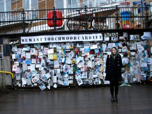  Elizabeth standing in front of the Torchwood fan shrine—a wall covered in Torchwood posters and so on—in Cardiff 