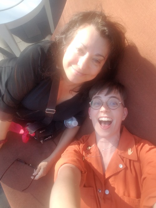  Annie Nocenti and Flourish pose on a sofa, holding the camera above their heads. It is very sunny. 