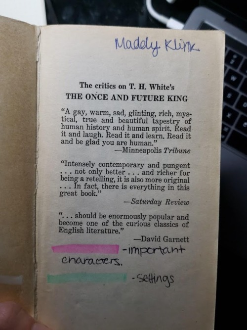  An old paperback copy of T.H. White’s  The Once and Future King , open to the front matter (laudatory quotes). The name “Maddy Klink” is written in a childish hand in the top right corner. A key is drawn in the blank space at the bottom of the page: pink highlighting denotes important characters, and green highlighting denotes settings. 