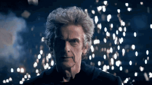 Animated gif of Peter Capaldi as the 12th Doctor walking in slow motion with sparks and papers flying in the background