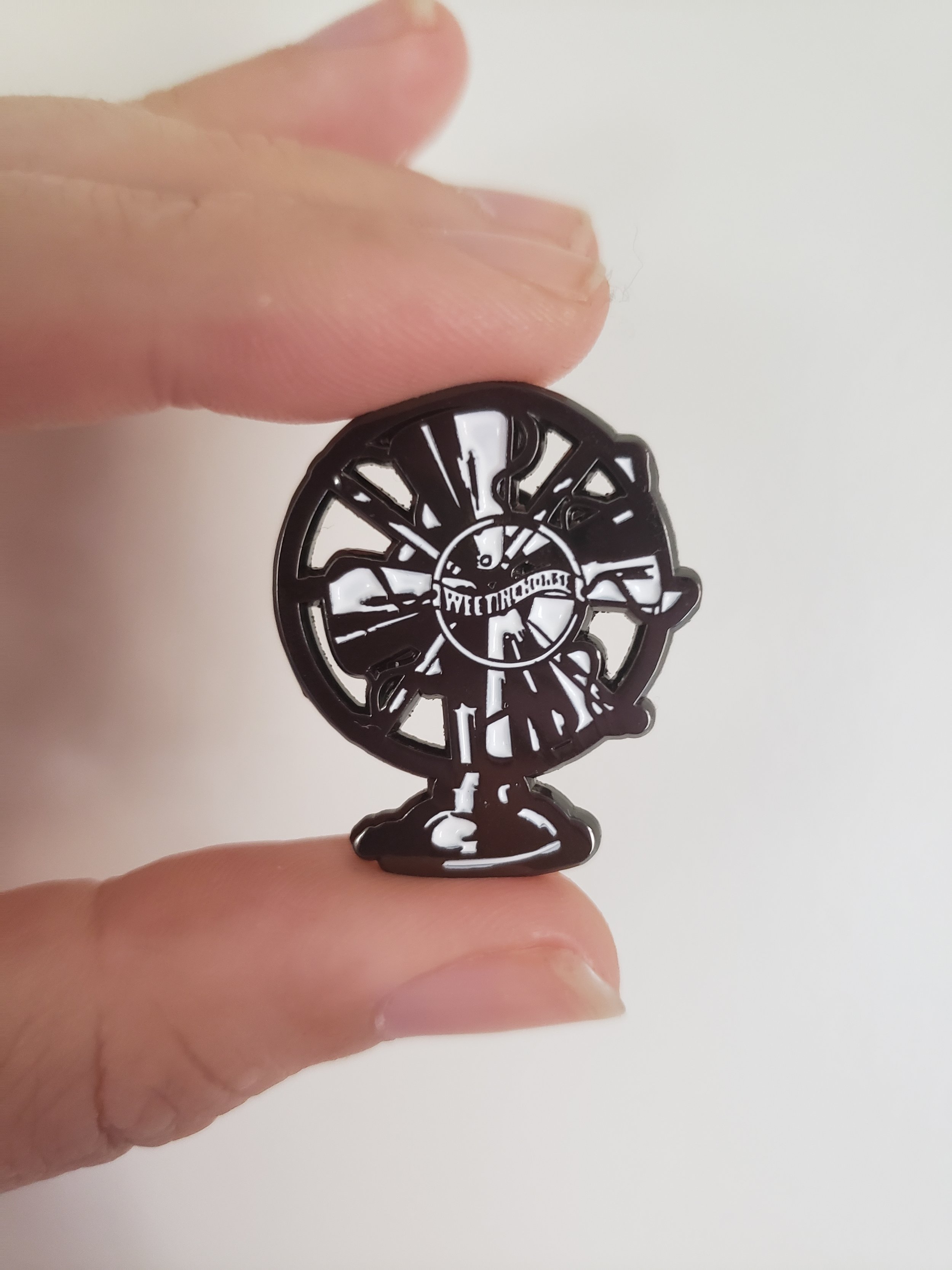  A small enamel pin of the Fansplaining logo. 