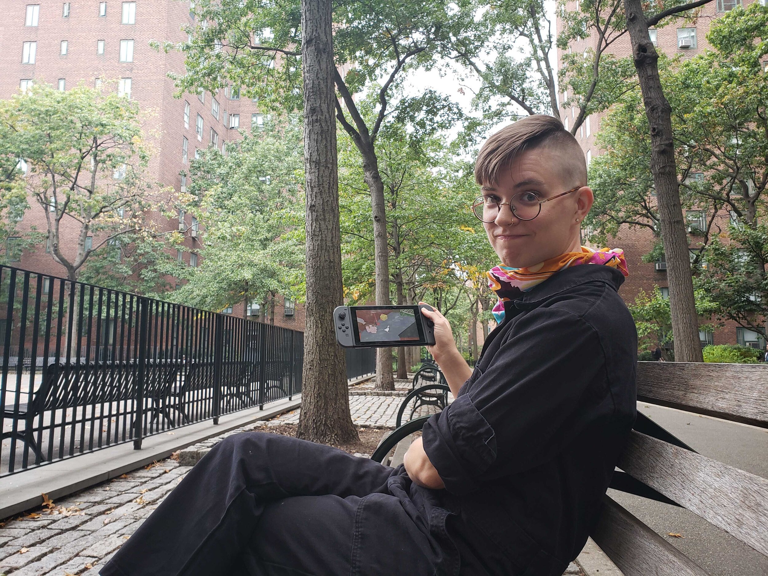  Flourish sits on a park bench playing “Untitled Goose Game.” 