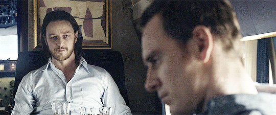 Animated gif of Charles Xavier and Erik Lehnsherr looking at each other seated on a plane