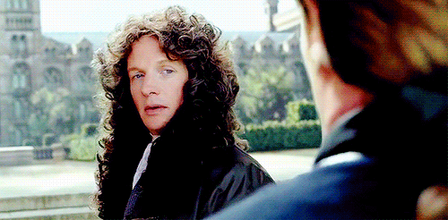 Animated gif of Thomas Hamilton turning to look at James McGraw while wearing a large dark curly (unsexy) wig.