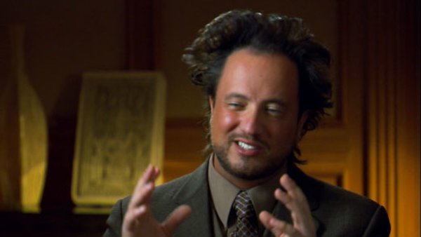 Still image of a man with wild hair gesturing with both hands