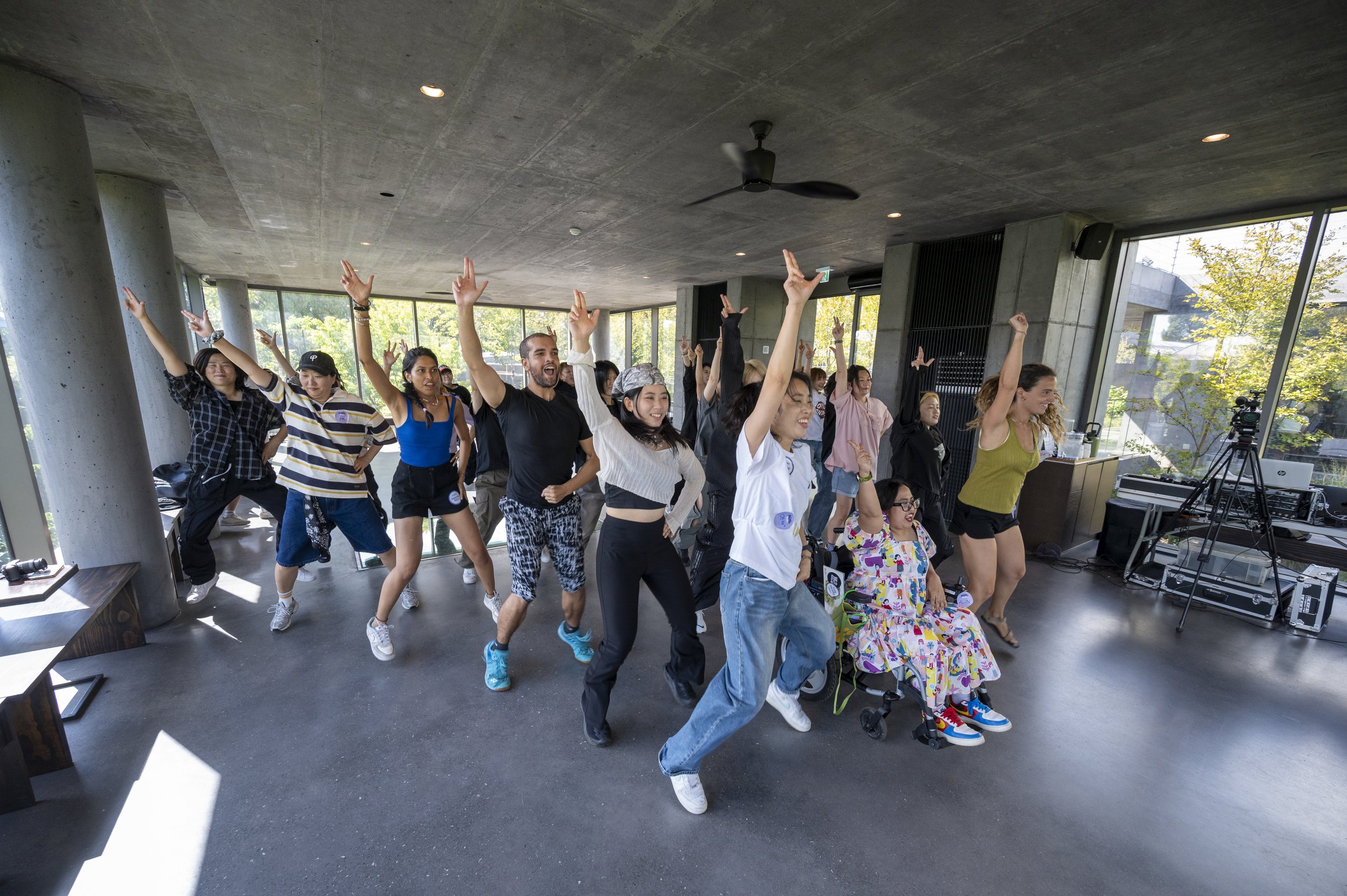 Image of a group of BTS fans learning a dance, with their right arms extended in the air.