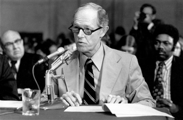  A man with a microphone in a tie, testifying before Congress. 