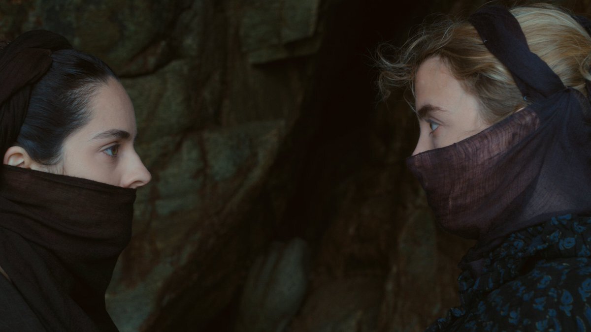 Portrait of a Lady on Fire's Marianne and Héloïse, mouths covered, gaze at each other