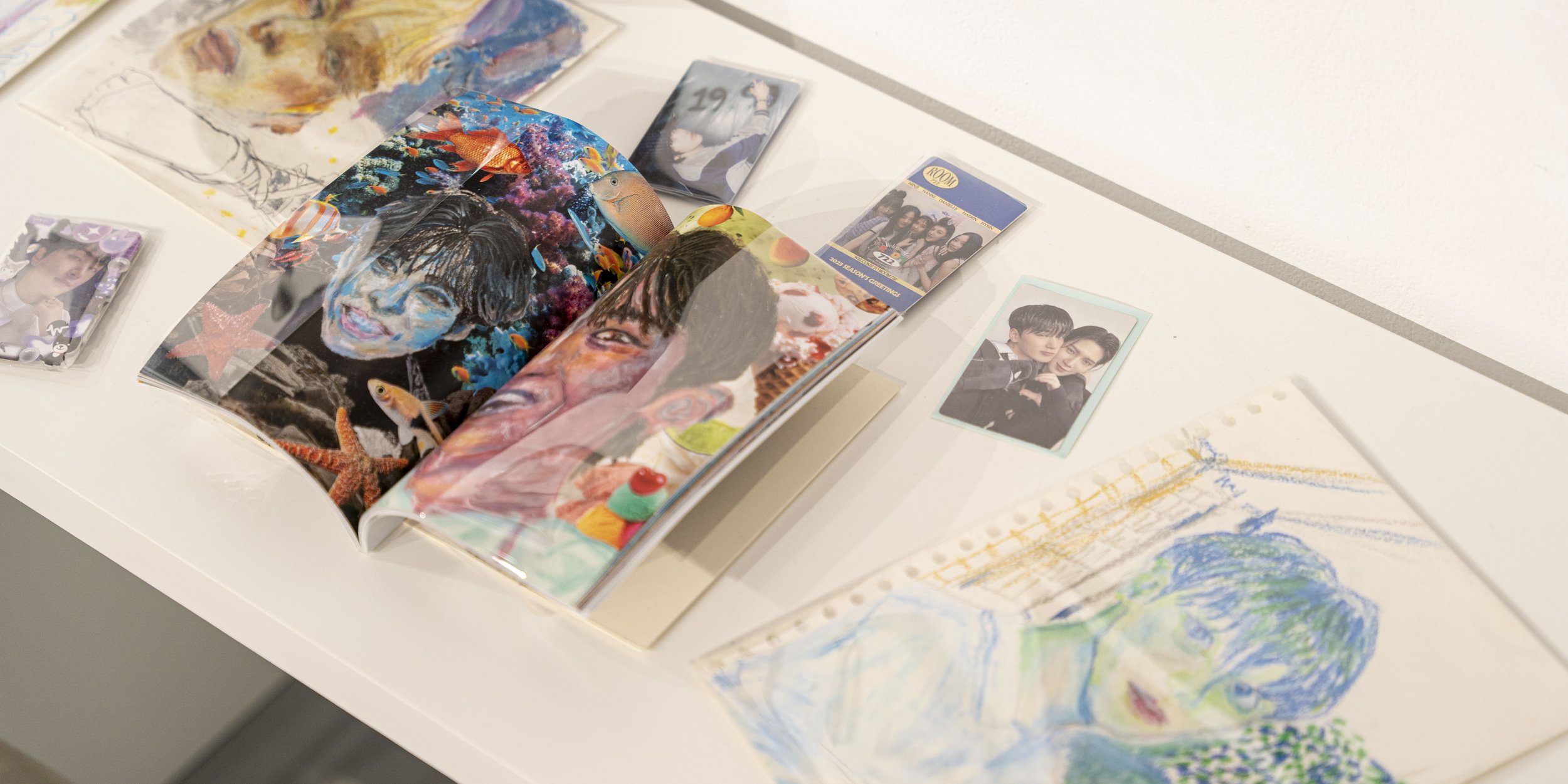 Selection of K-pop fanart on a table.