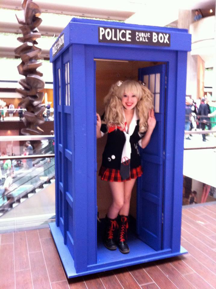 Photograph of Allegra in cosplay, standing inside a blue police box