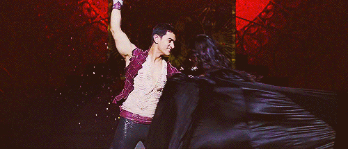  An EXTREMELY BOLLYWOOD MOMENT in animated gif format featuring a man and a woman embracing dramatically as the woman drops her black cloak. 