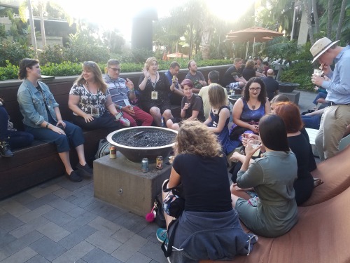  About 11 people gather around an outdoor fire pit at the San Diego Marriott, drinking and chatting. 