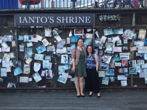  Elizabeth and Dr. Naomi Jacobs standing in front of Ianto’s Shrine, a wall covered in flyers and photographs fans have tacked up commemorating Ianto from  Torchwood . 