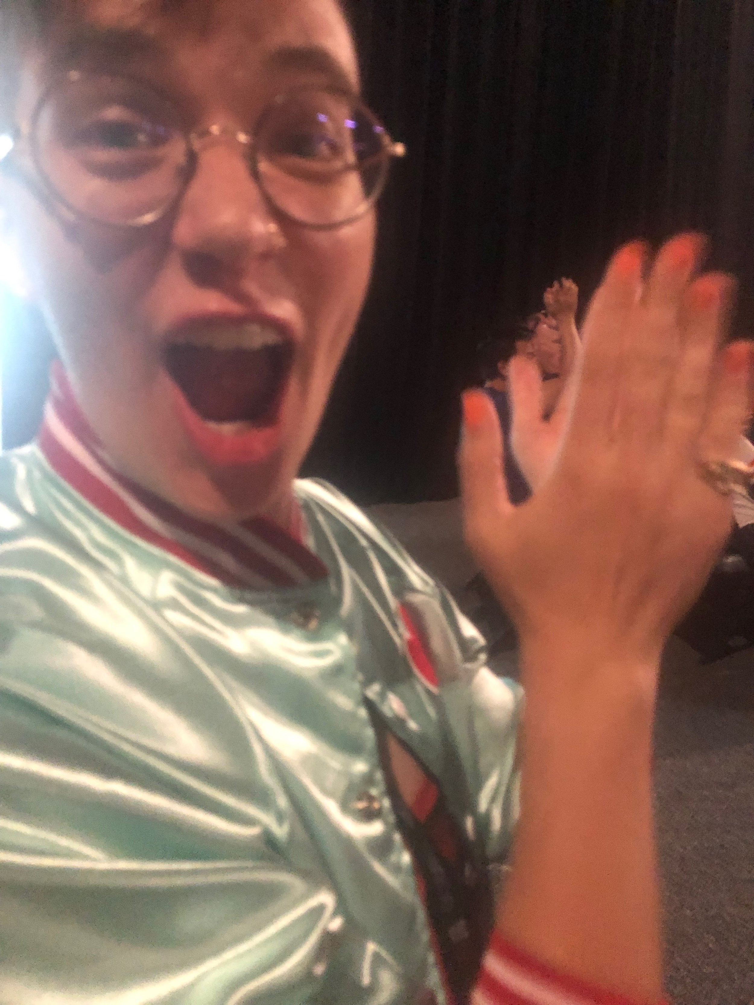 Photograph of Flourish looking THRILLED, their mouth open while clapping