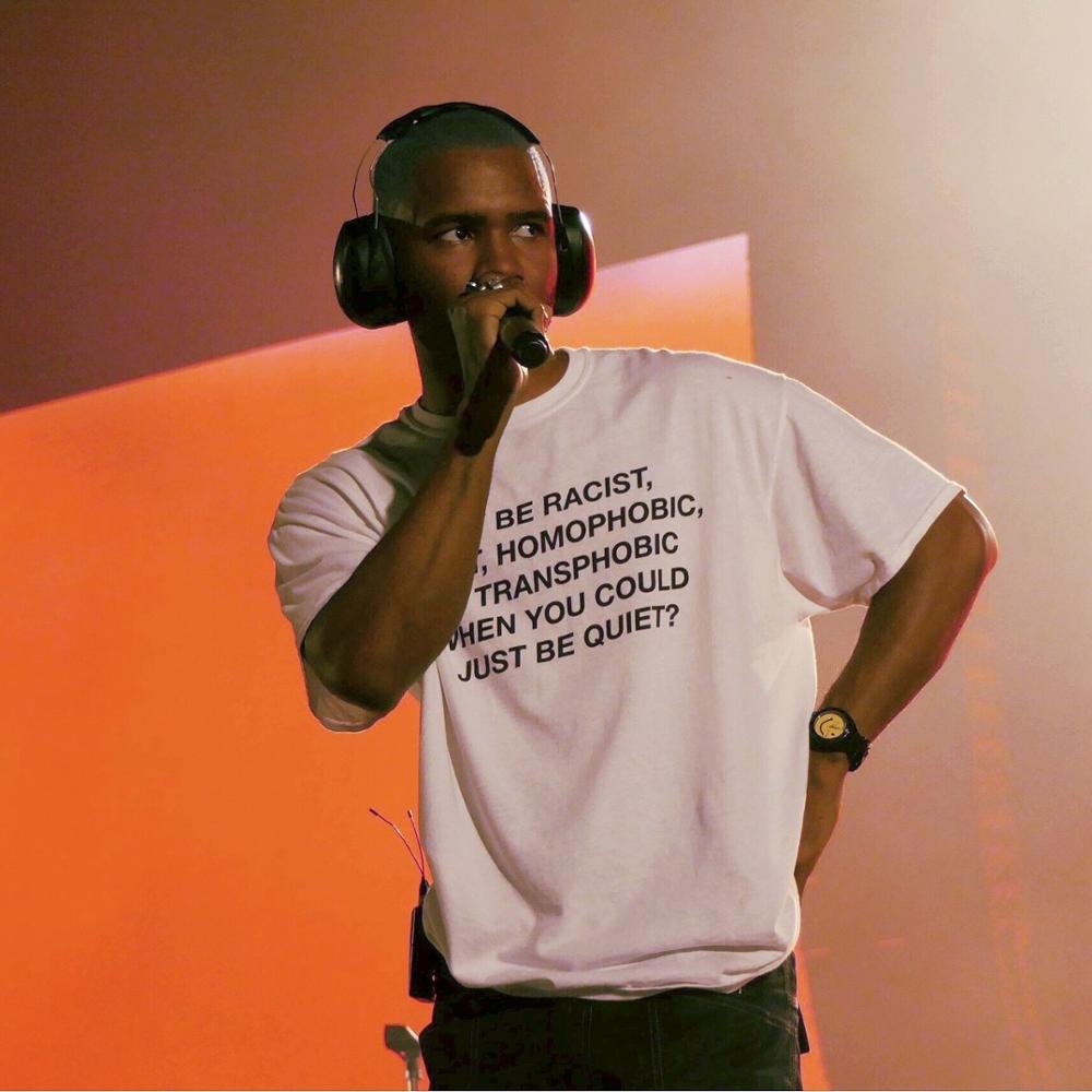 Photograph of Frank Ocean wearing headphones and holding a mic. The t-shirt reads WHY BE RACIST, HOMOPHOBIC, AND TRANSPHOBIC WHEN YOU COULD JUST BE QUIET?