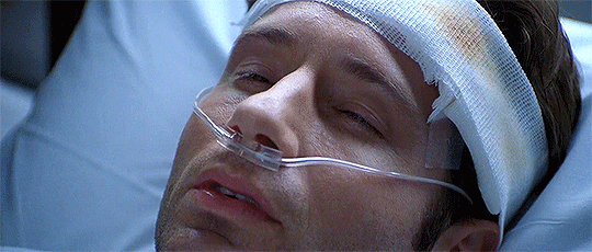 Animated gif: closeup of Mulder in a hospital bed with a bandage on his forehead