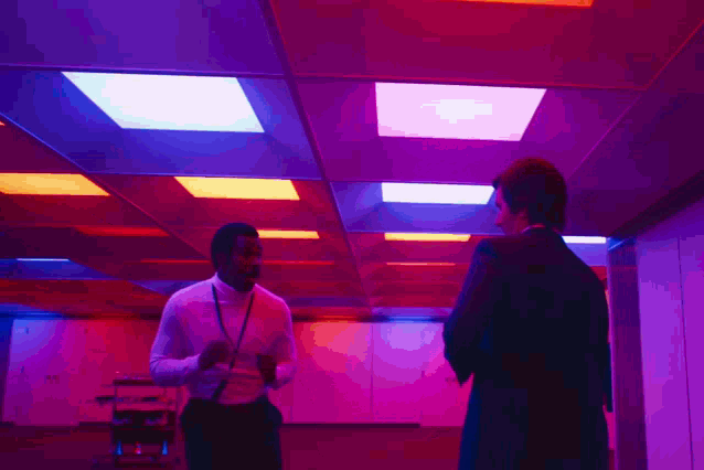 Animated gif of Mark and Milchick from Severance dancing as colored lights flash